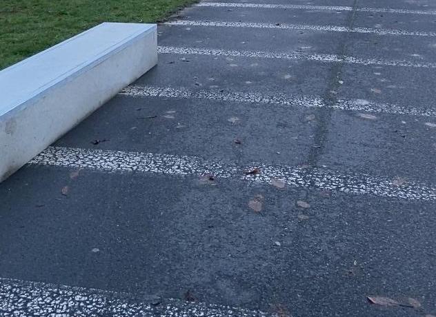 Eine Betonledge mit Metallkanten am Rande einer Asphaltflaeche